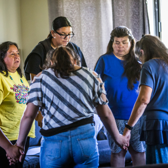 People hold hands in a circle at the Lakota Youth Shelter at Pine Ridge Reservation