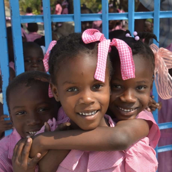 Schoolgirls smile in pink uniforms in Haiti