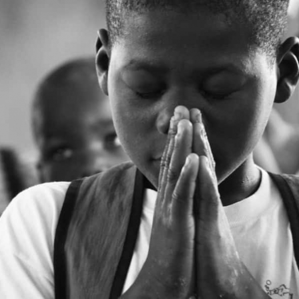 Child prays in Haiti